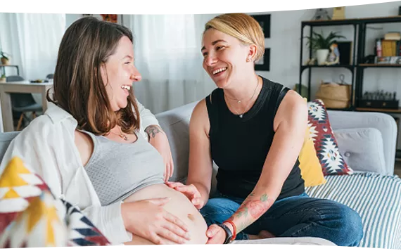 Pregnant woman and friend touching stomach